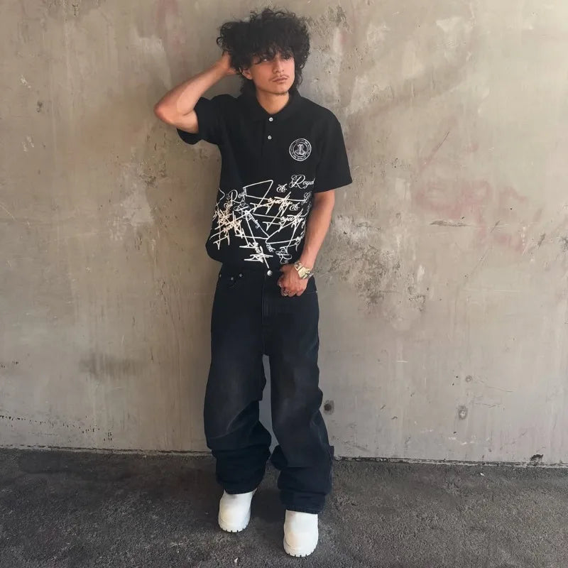 Black polo shirt with white text and logo on a concrete floor